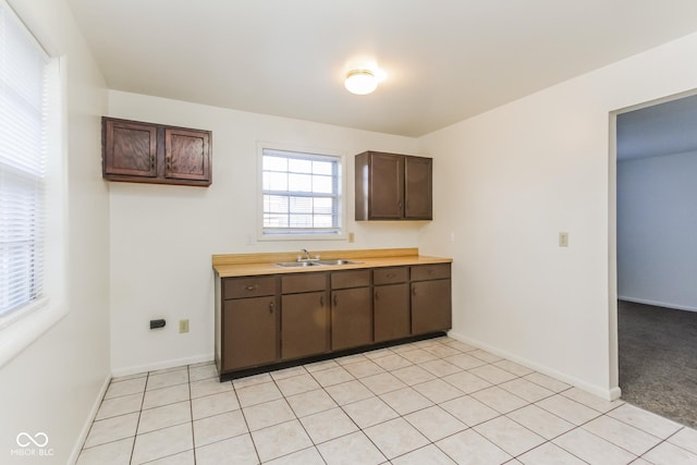 kitchen featuring sink, light tile patterned floors, and dark brown cabinets