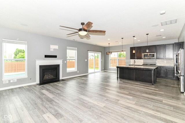 1324 Trailside Dr, Greenwood, IN 46143 - kitchen with stainless steel microwave, a sink, a ceiling fan, open floor plan, and light wood-style floors