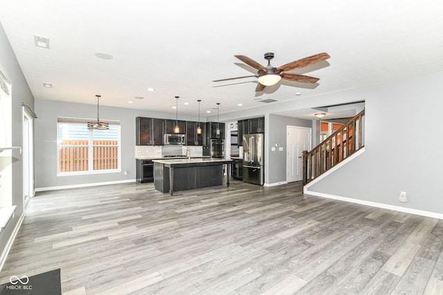 1324 Trailside Dr, Greenwood, IN 46143 - kitchen featuring appliances with stainless steel finishes, open floor plan, a ceiling fan, baseboards, and light wood-style floors