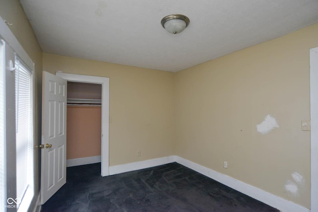 unfurnished bedroom with a closet and dark colored carpet