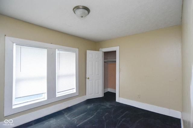 unfurnished bedroom with dark carpet and a textured ceiling