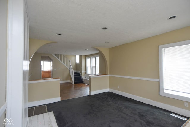 unfurnished room featuring dark carpet and a wealth of natural light