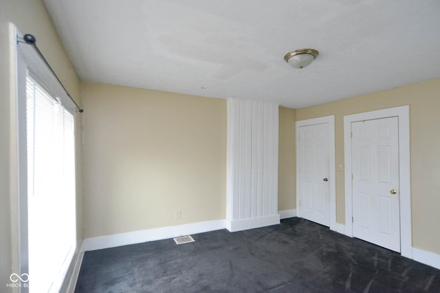 unfurnished bedroom with dark colored carpet