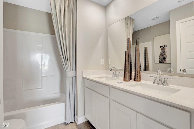 full bathroom with vanity, shower / tub combo with curtain, a textured ceiling, and toilet