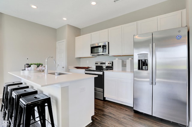 kitchen with stainless steel appliances, sink, an island with sink, and white cabinets