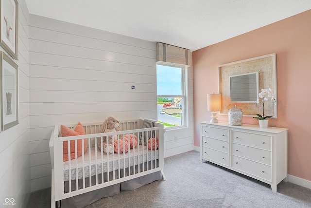 carpeted bedroom featuring a nursery area and wood walls