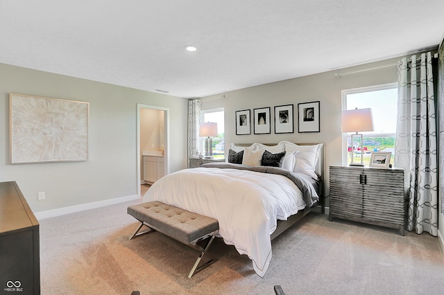 carpeted bedroom featuring ensuite bath and a textured ceiling