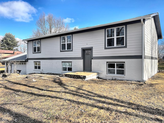 raised ranch featuring a garage and brick siding