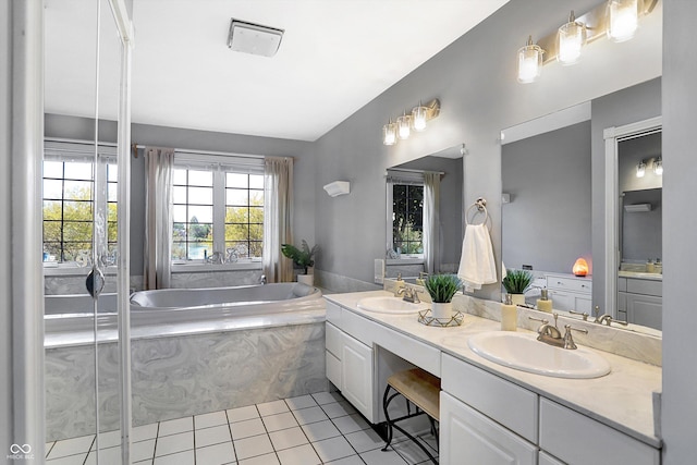 bathroom featuring tile patterned flooring, vanity, and tiled bath