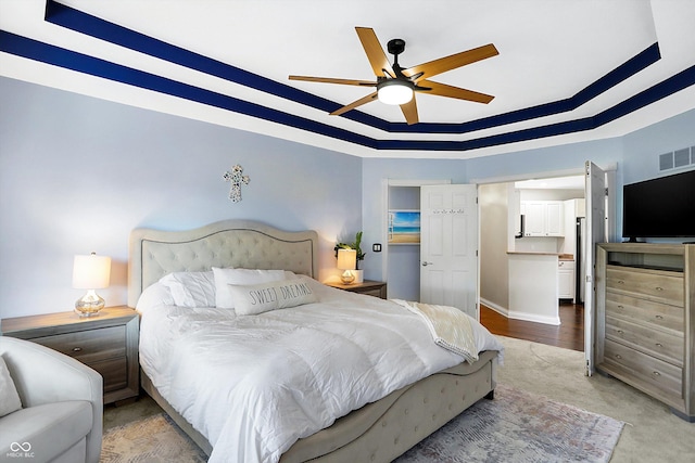 bedroom with ceiling fan and a tray ceiling