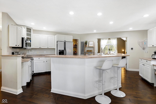 kitchen featuring a kitchen island, appliances with stainless steel finishes, dark wood-type flooring, and white cabinets