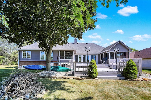 back of house with a wooden deck, a yard, and a sunroom