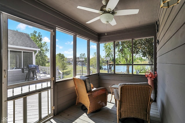 sunroom featuring a water view and ceiling fan