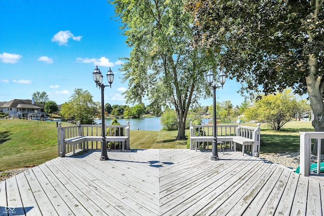 wooden terrace with a water view and a yard