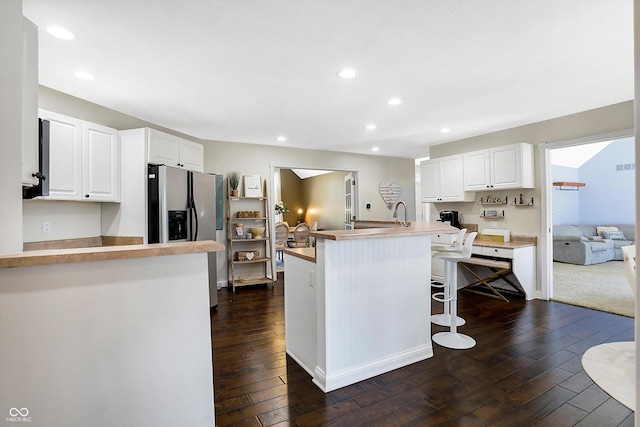 kitchen featuring white cabinetry, kitchen peninsula, a kitchen bar, and stainless steel fridge with ice dispenser