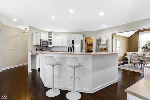 kitchen featuring fridge with ice dispenser, dark hardwood / wood-style floors, a kitchen breakfast bar, a large island, and white cabinets