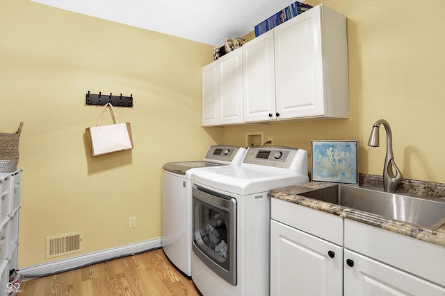 laundry room featuring cabinets, separate washer and dryer, sink, and light hardwood / wood-style flooring