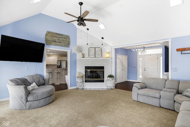 living room featuring ceiling fan, a large fireplace, high vaulted ceiling, and carpet floors