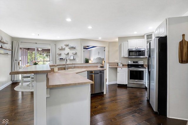 kitchen featuring appliances with stainless steel finishes, dark hardwood / wood-style floors, an island with sink, sink, and white cabinets