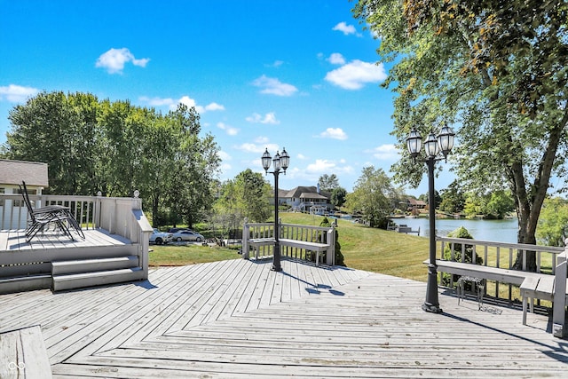 wooden terrace featuring a water view and a yard