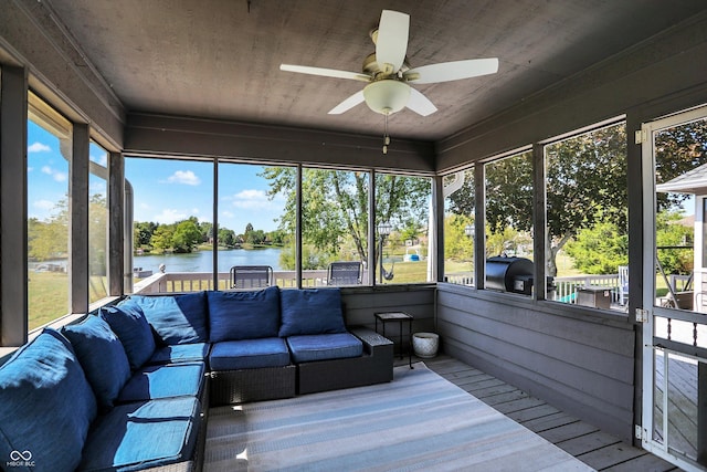 sunroom / solarium with ceiling fan and a water view