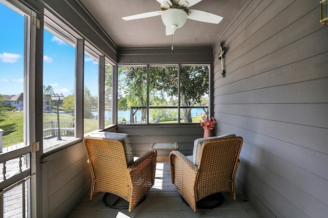 sunroom featuring a water view and ceiling fan