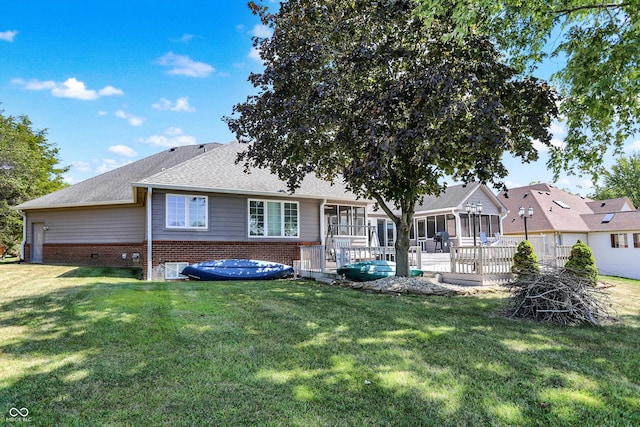 back of property featuring a lawn, a sunroom, and a deck