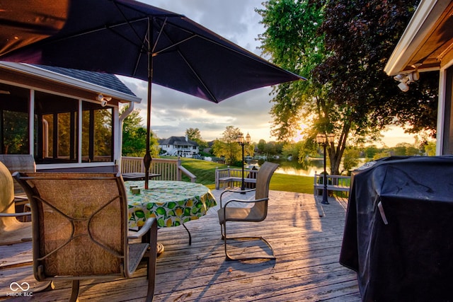 deck at dusk featuring a grill and a sunroom