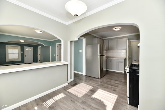 kitchen featuring range, stainless steel refrigerator, gray cabinets, hardwood / wood-style flooring, and decorative backsplash