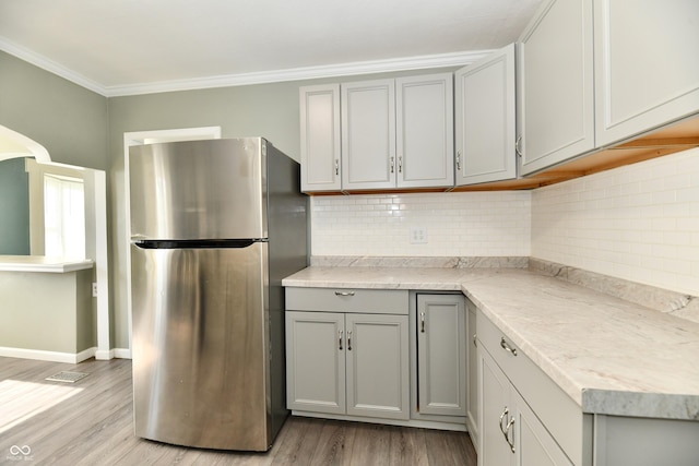 kitchen featuring crown molding, gray cabinets, and stainless steel refrigerator