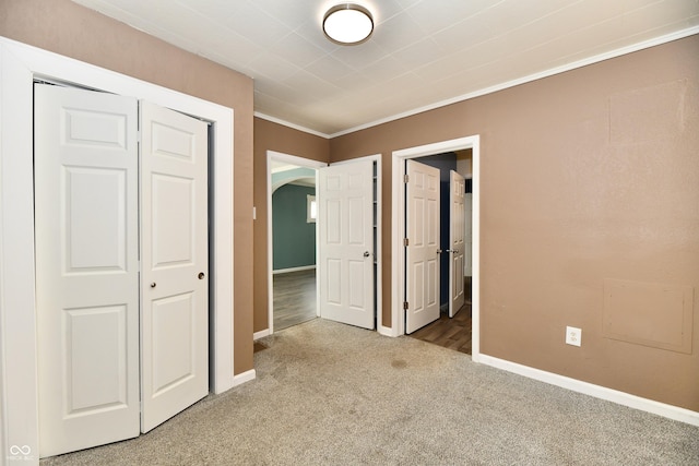 unfurnished bedroom featuring ornamental molding, carpet floors, and a closet