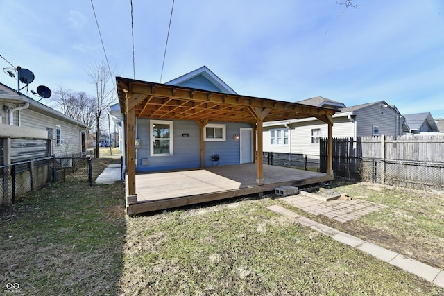 rear view of property featuring a wooden deck and a lawn