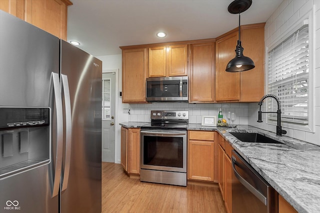 kitchen with sink, tasteful backsplash, decorative light fixtures, stainless steel appliances, and light stone countertops