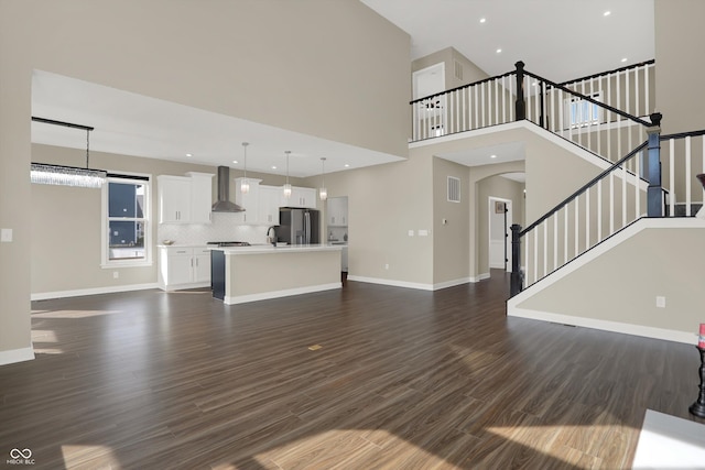 unfurnished living room featuring a high ceiling, dark hardwood / wood-style floors, and sink