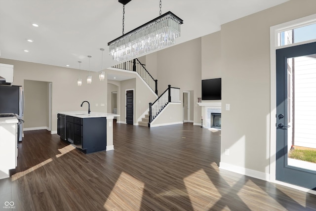 interior space with pendant lighting, dark hardwood / wood-style floors, an island with sink, and dishwasher