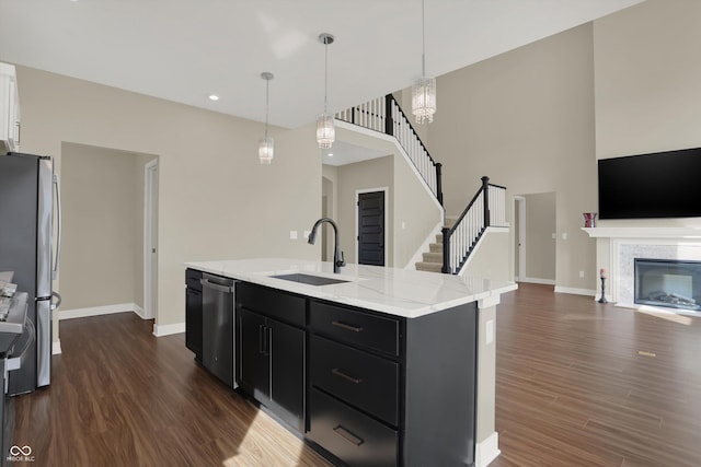 kitchen featuring appliances with stainless steel finishes, decorative light fixtures, an island with sink, sink, and dark hardwood / wood-style flooring