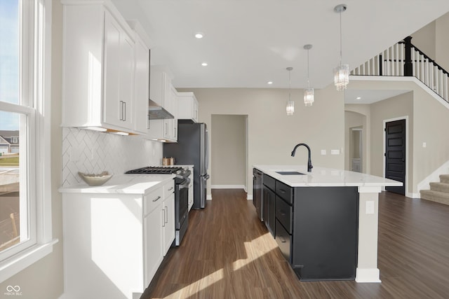 kitchen featuring sink, appliances with stainless steel finishes, hanging light fixtures, an island with sink, and white cabinets