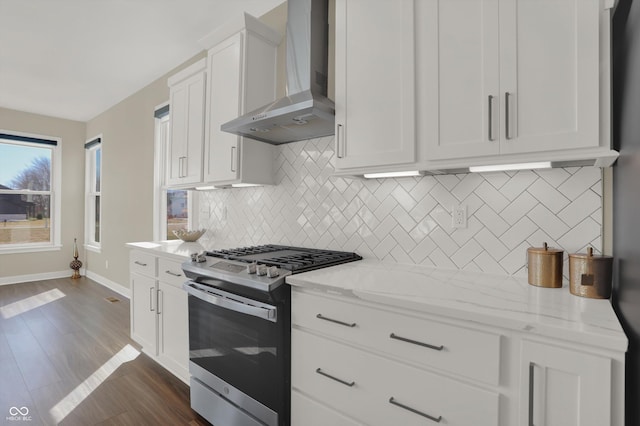 kitchen featuring white cabinets, light stone countertops, stainless steel gas stove, and wall chimney range hood