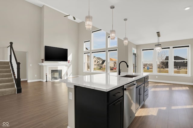 kitchen featuring pendant lighting, stainless steel dishwasher, sink, and a center island with sink