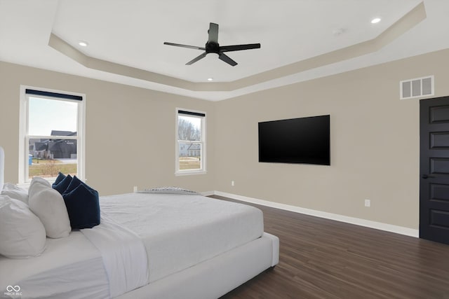 bedroom featuring dark hardwood / wood-style floors, a raised ceiling, and ceiling fan