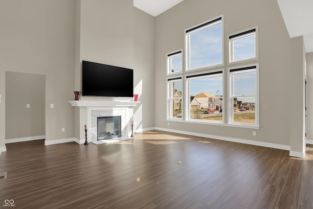 unfurnished living room featuring a towering ceiling, dark hardwood / wood-style floors, and a wealth of natural light