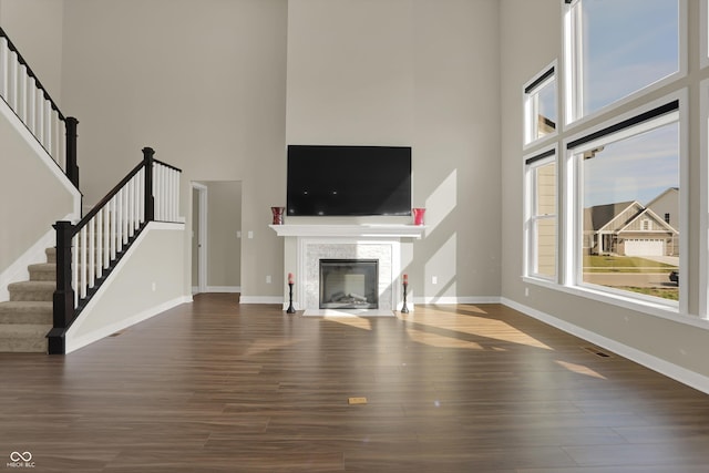 unfurnished living room with a towering ceiling, a wealth of natural light, and dark hardwood / wood-style floors