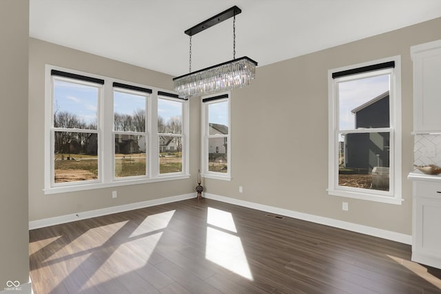 unfurnished dining area with dark hardwood / wood-style flooring and an inviting chandelier