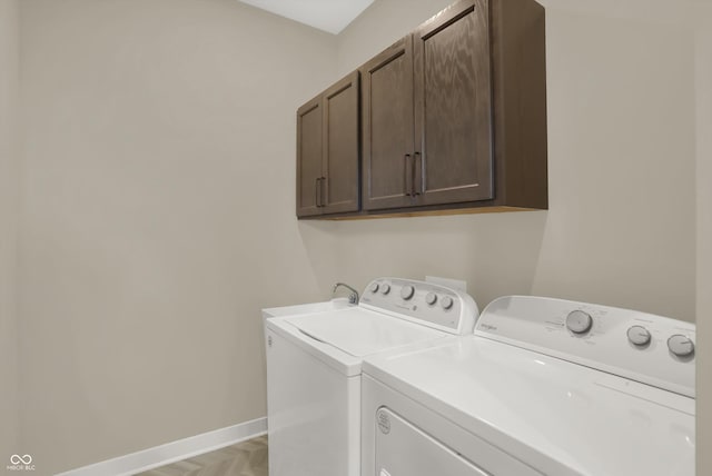 washroom featuring cabinets, light parquet floors, and washing machine and clothes dryer