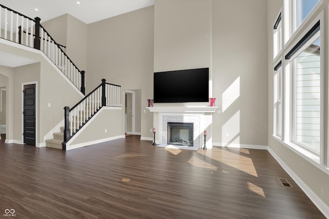 unfurnished living room featuring a high ceiling and dark hardwood / wood-style floors