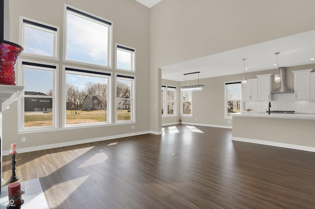 unfurnished living room featuring sink, a towering ceiling, and dark wood-type flooring