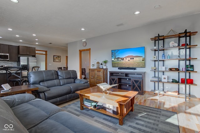 living area with light wood finished floors, recessed lighting, and a textured ceiling