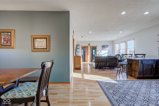 dining space with recessed lighting, baseboards, a textured ceiling, and light wood-style flooring