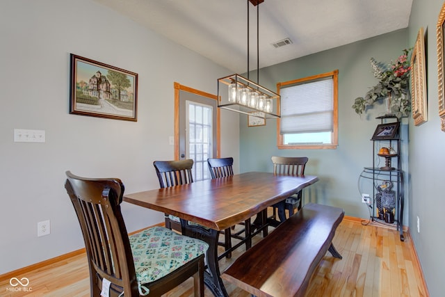 dining space featuring light wood-type flooring, visible vents, and baseboards