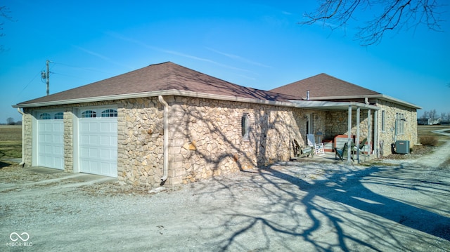 view of property exterior featuring a garage, stone siding, and a shingled roof